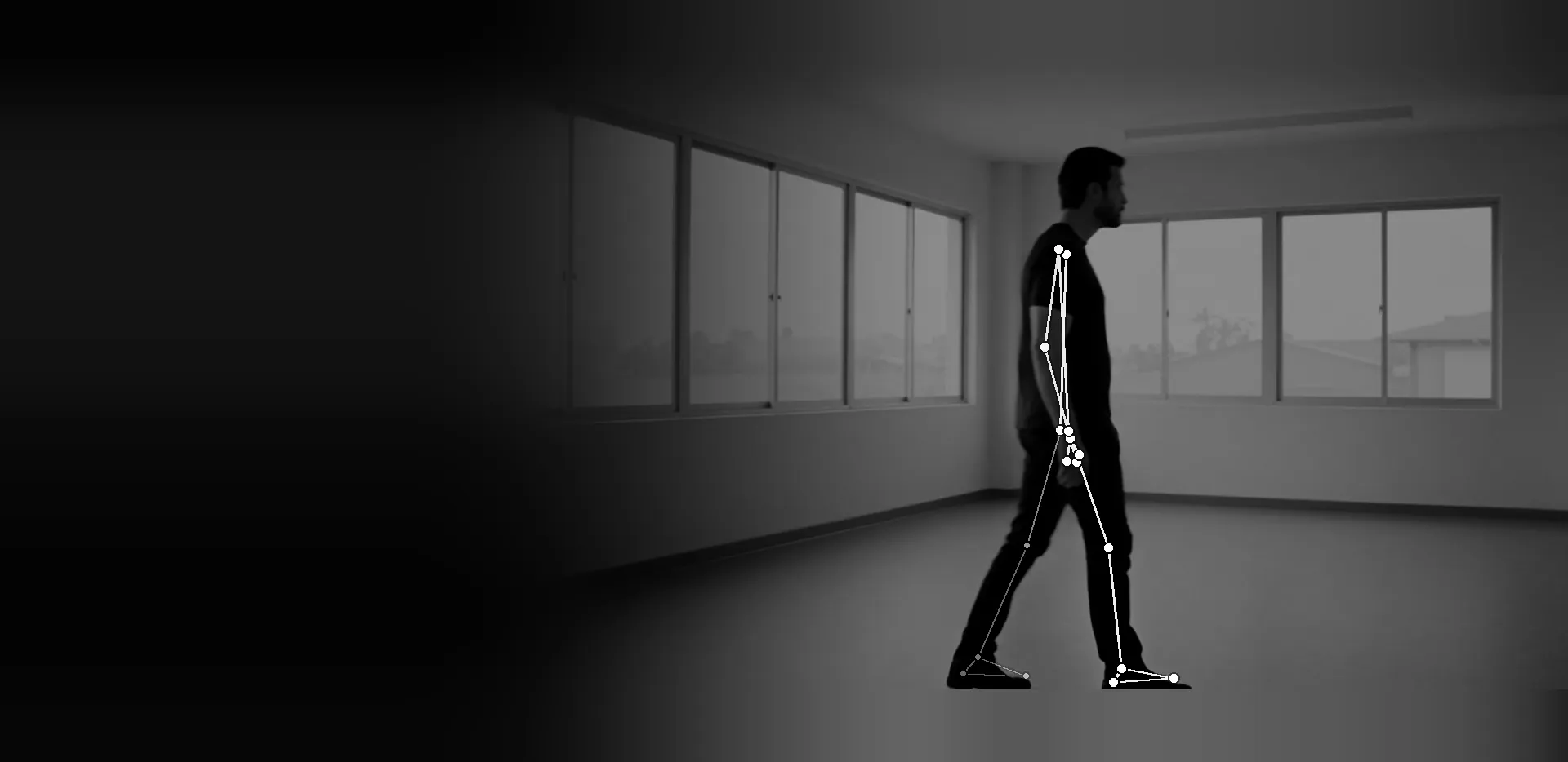 A person walking from left to right across an empty room with wide windows, seen from the side, with the joint points and connecting lines found by a pose estimation model drawn over the black-and-white scene